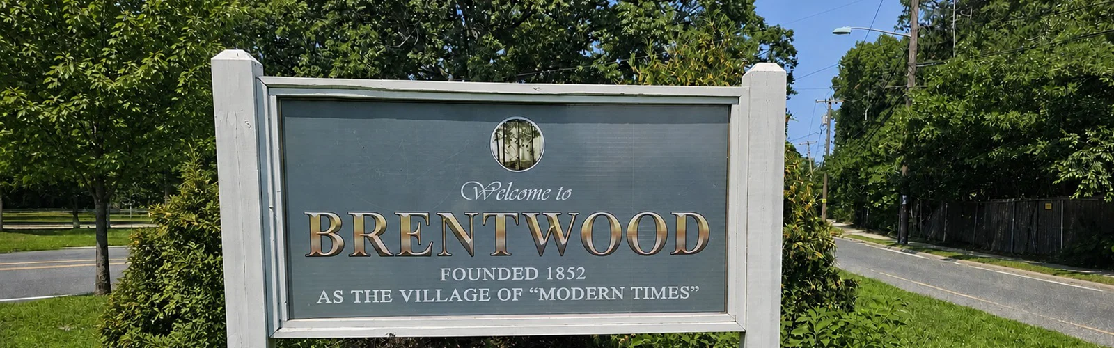 Welcome to Brentwood sign along a tree-lined road in Brentwood, New York